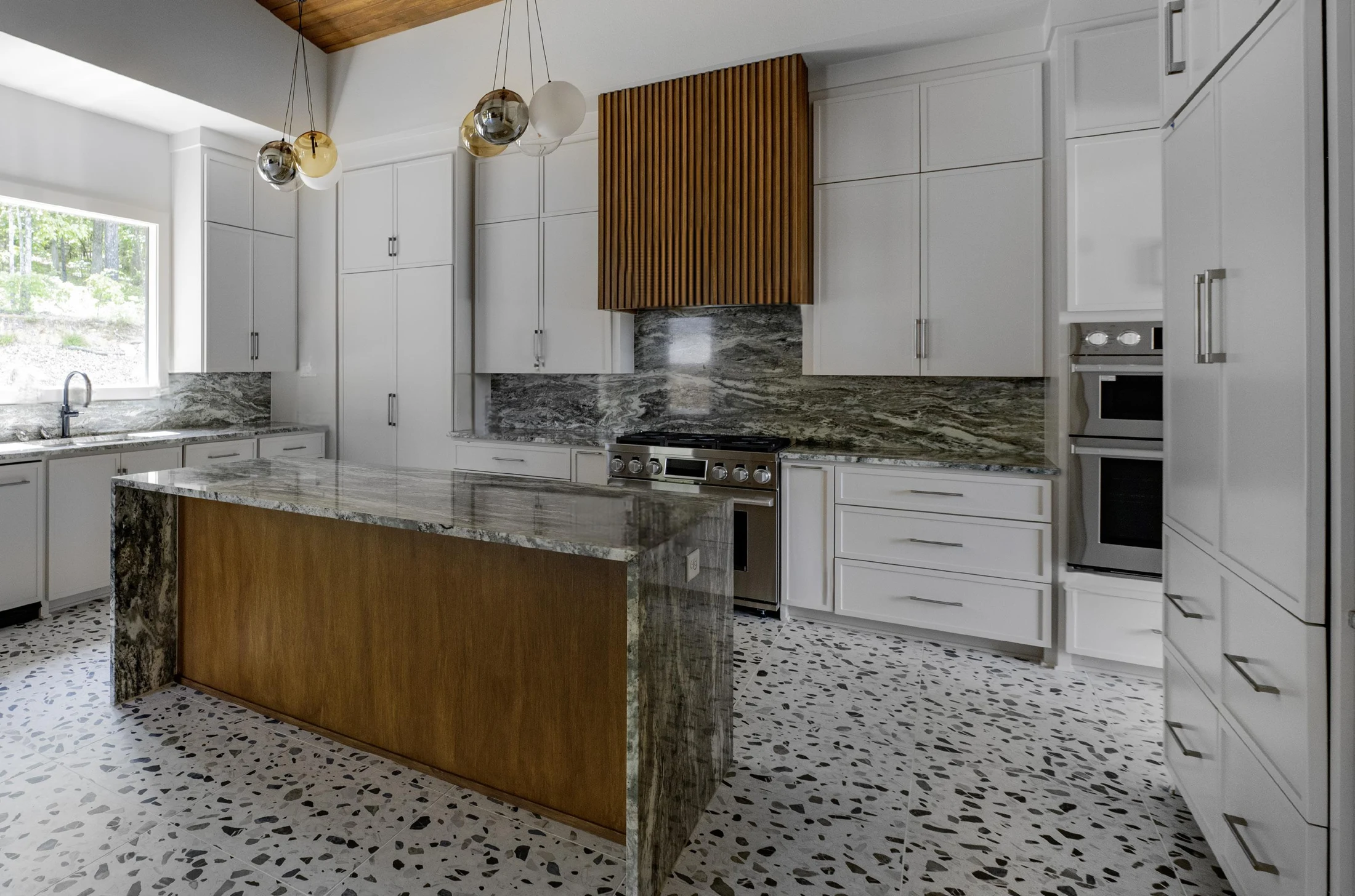 Wood, stone, and terrazzo meet in a bright, open kitchen.