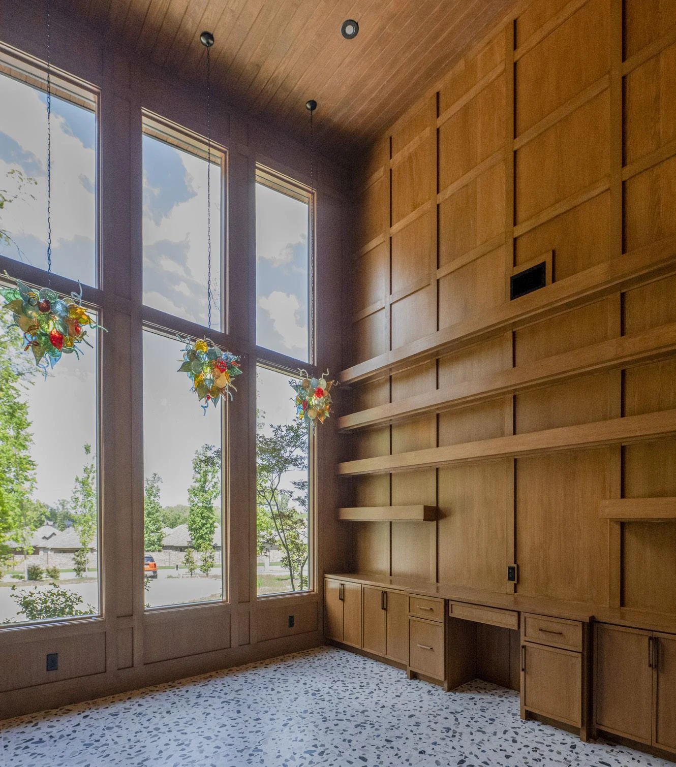 Warm wood paneling, built-in shelving, and dramatic windows define the study.